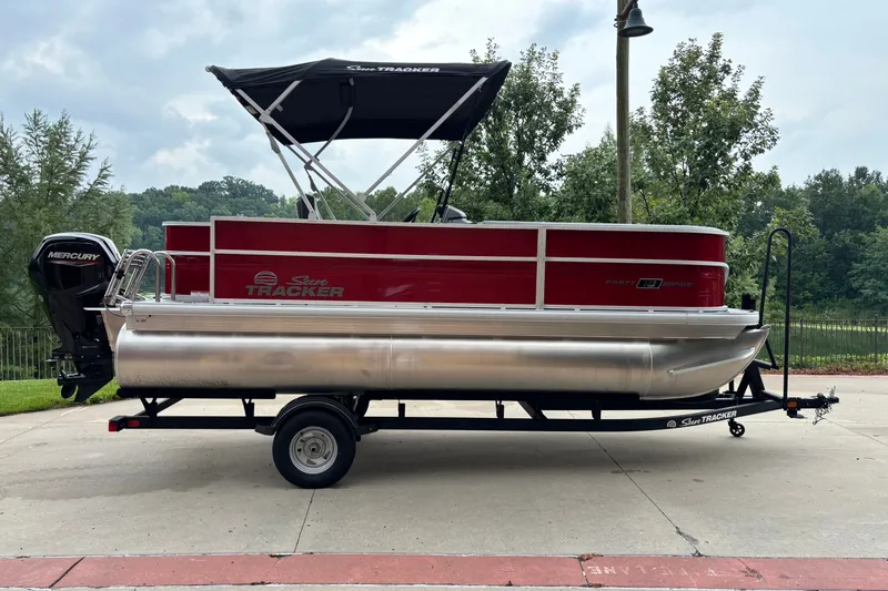 The Image of 2026 Sun Tracker Party Barge 18 DLX pontoon boat on trailer, parked outdoors. - 0