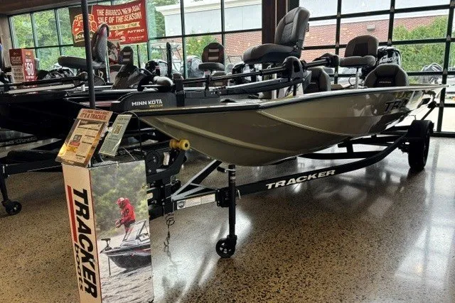 The Image of 2026 Tracker Pro Team 175 boat displayed indoors, featuring Minn Kota motor and promotional signage. - 0