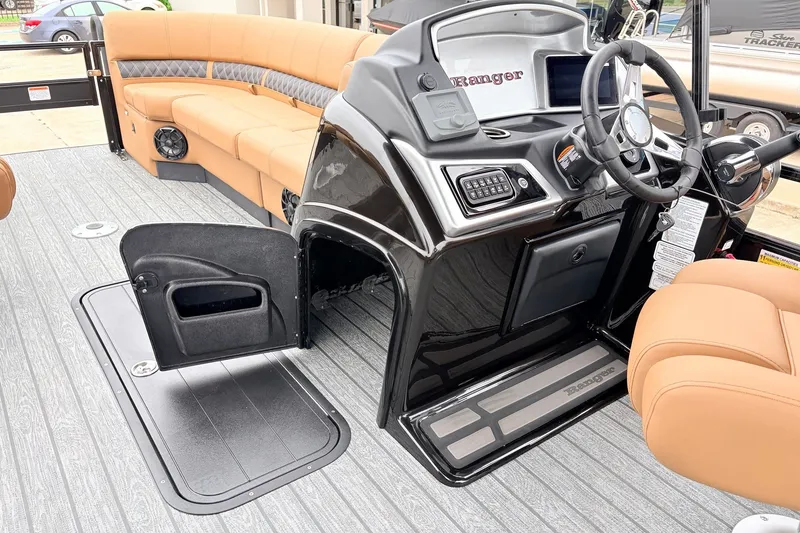 Slide: The Image of 2026 Ranger 223FC boat interior with steering console, tan seating, and open storage compartment. - 28