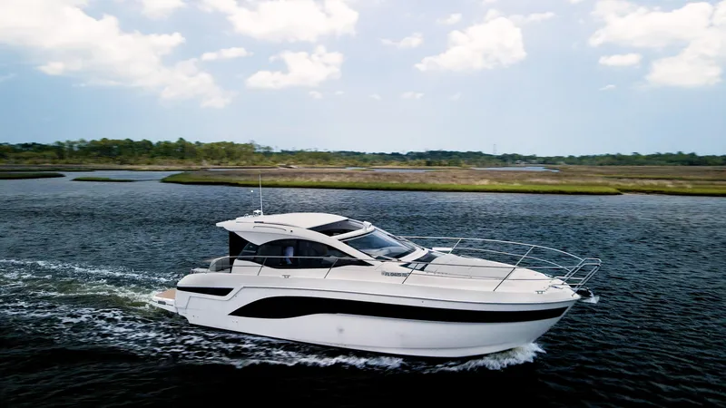 Slide: The Image of Bavaria SR41 2022 yacht cruising on a serene waterway under a partly cloudy sky. - 1