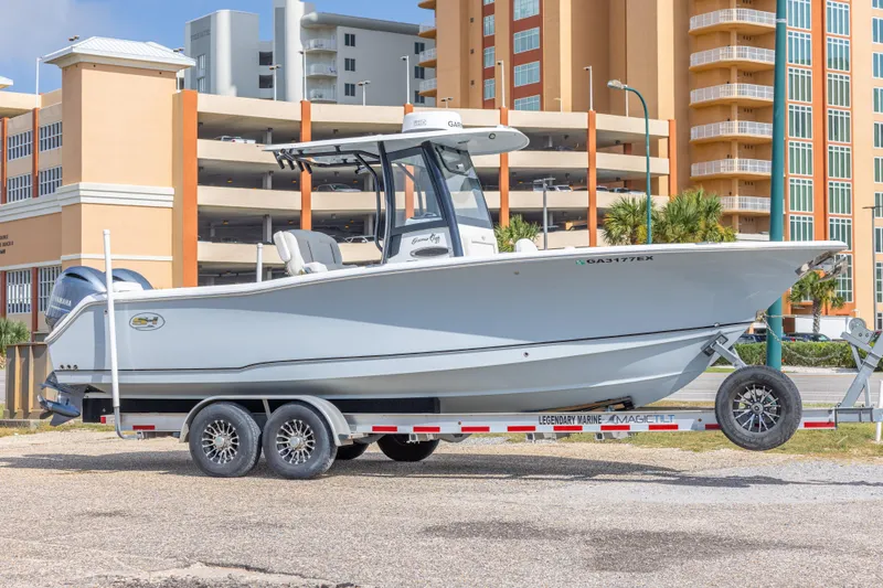 The Image of 2022 Sea Hunt Gamefish 27 boat on trailer, parked near modern buildings. - 1