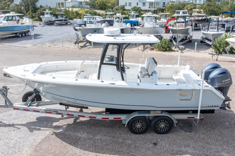 Slide: The Image of 2022 Sea Hunt Gamefish 27 boat on trailer, parked in a marina with other boats. - 9