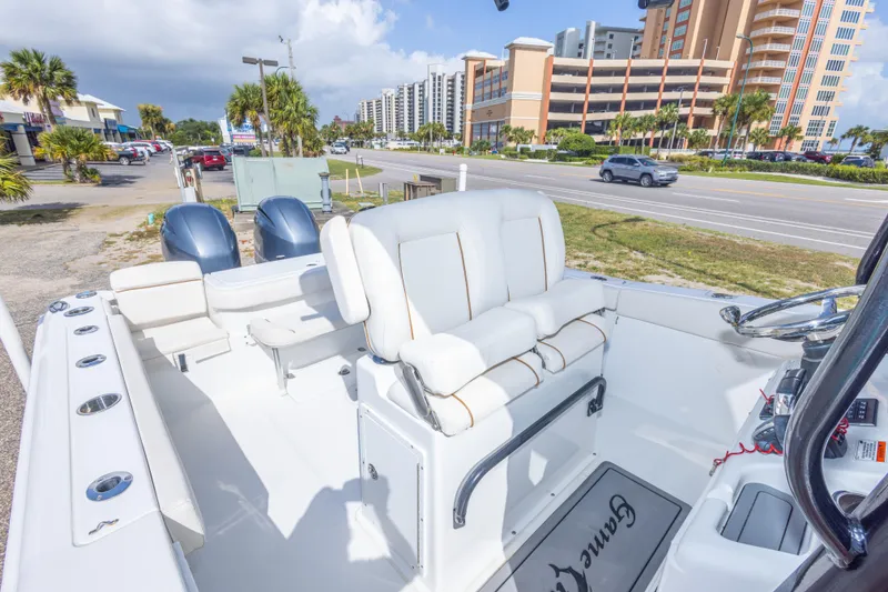 Slide: The Image of 2022 Sea Hunt Gamefish 27 boat interior with seating and dual engines, parked near a road. - 34