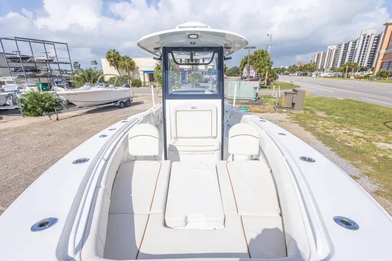 Slide: The Image of 2022 Sea Hunt Gamefish 27 boat with spacious seating, docked near a coastal road. - 29
