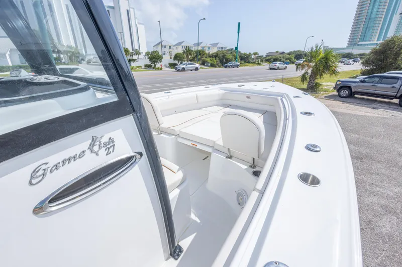 Slide: The Image of 2022 Sea Hunt Gamefish 27 boat with sleek white interior and coastal backdrop. - 22