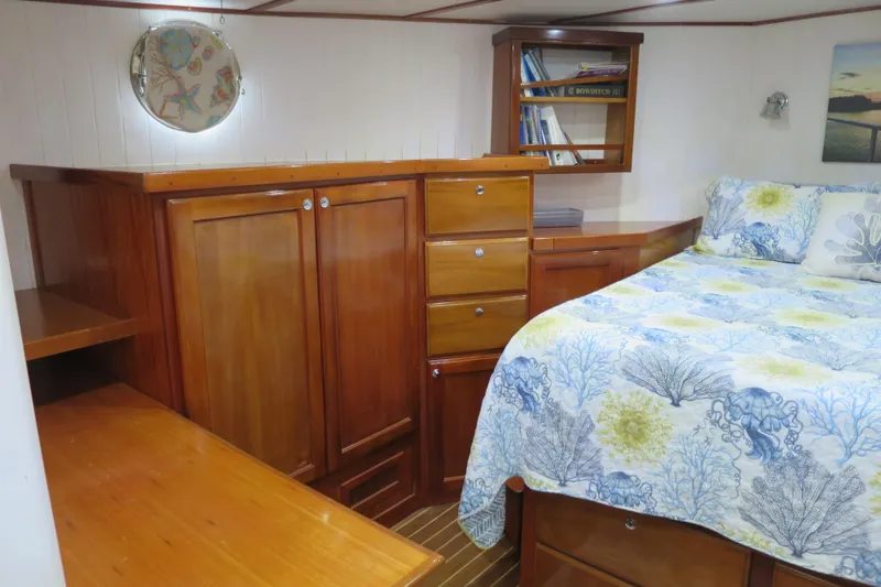 Slide: The Image of Cozy 2007 Grand Harbour N47 yacht cabin with wooden furniture and nautical-themed bedding. - 19