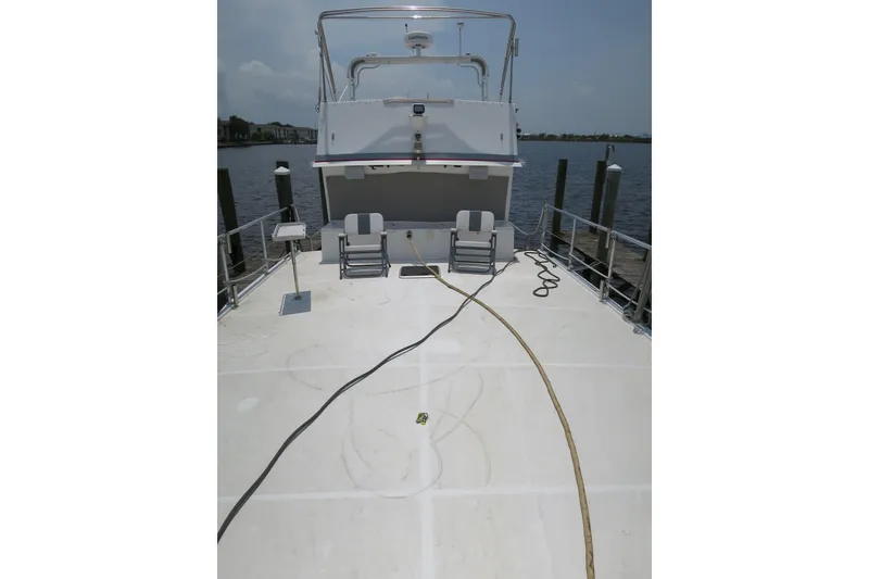 Slide: The Image of 2007 Grand Harbour N47 yacht deck with chairs and equipment, docked by the water. - 13