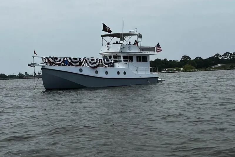 Slide: The Image of 2007 Grand Harbour N47 yacht adorned with festive bunting, cruising on a calm waterway. - 2