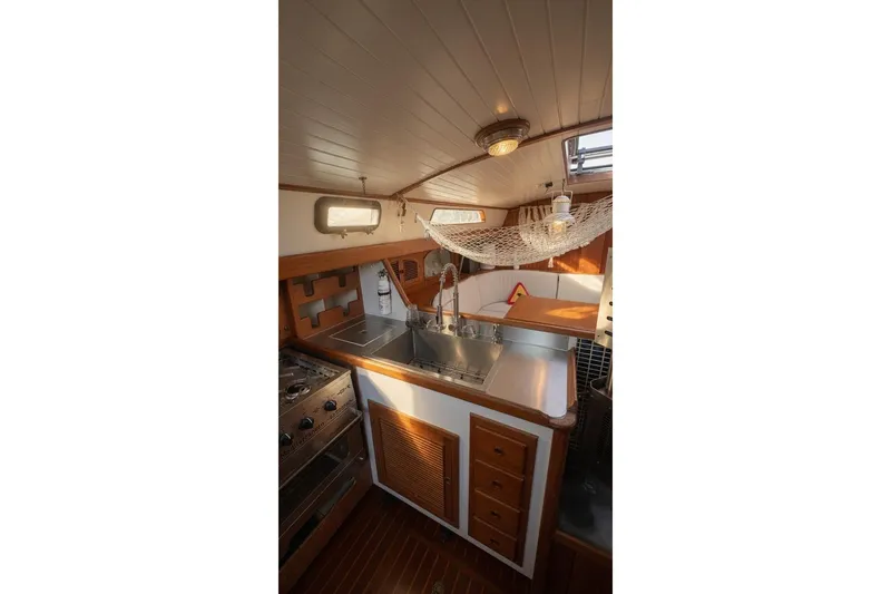 Slide: The Image of 1980 Passport 40 yacht interior kitchen with wooden cabinetry and stainless steel sink. - 5