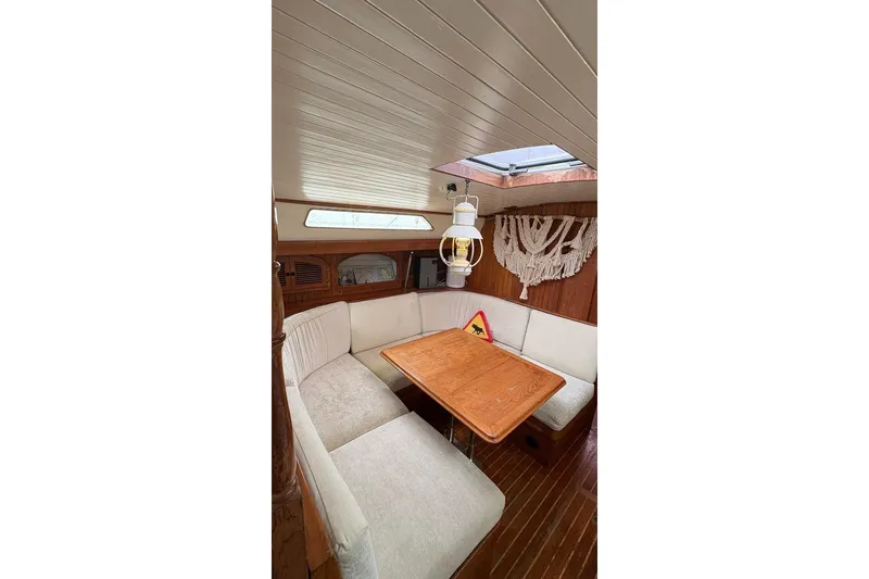 Slide: The Image of Cozy interior of 1980 Passport 40 sailboat with wooden table and cushioned seating. - 7