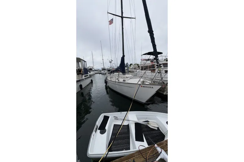 Slide: The Image of 1980 Passport 40 sailboat docked in a marina, overcast sky, small boat in foreground. - 3