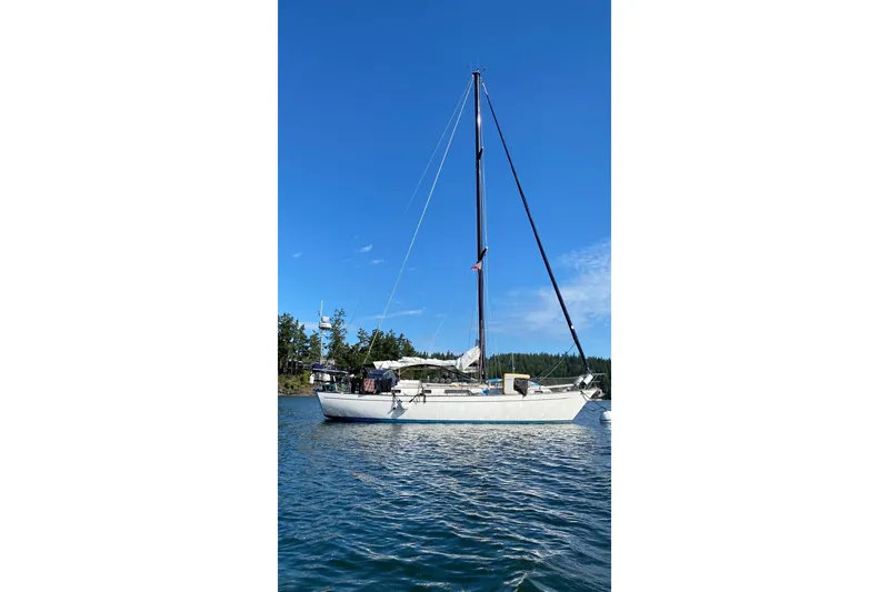 Slide: The Image of 1980 Passport 40 sailboat anchored on calm water under clear blue sky. - 1