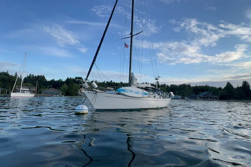 The Image of Sailboat on calm water, Passport 40 model, 1980, with scenic shoreline backdrop. - 0