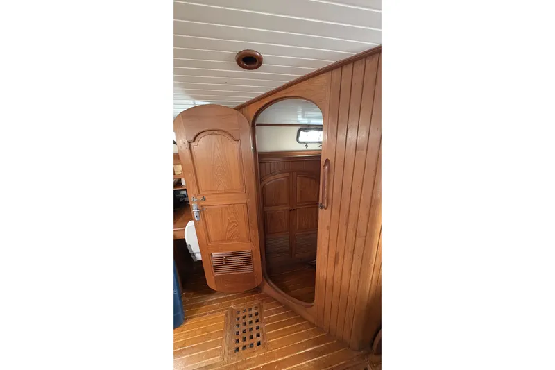 Slide: The Image of Wooden interior of a 1980 Passport 40 sailboat, featuring a door and storage area. - 29