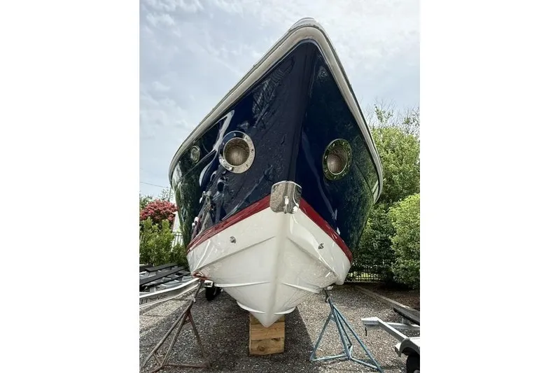 Slide: The Image of 2012 Cobalt 276 boat on stands, blue hull with red stripe, outdoors. - 2