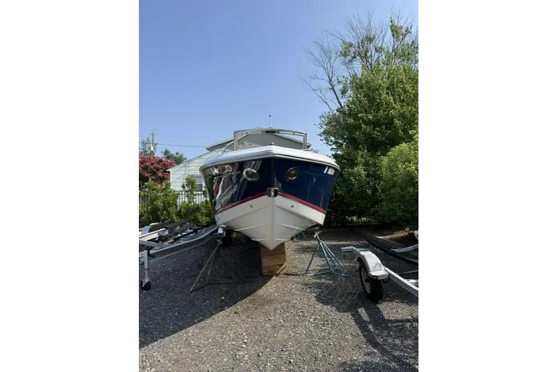 Slide: The Image of 2012 Cobalt 276 boat on trailer, parked outdoors with trees in background. - 3