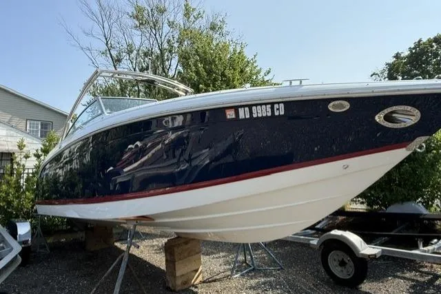 The Image of 2012 Cobalt 276 boat on trailer, parked outdoors, with trees and house in background. - 0
