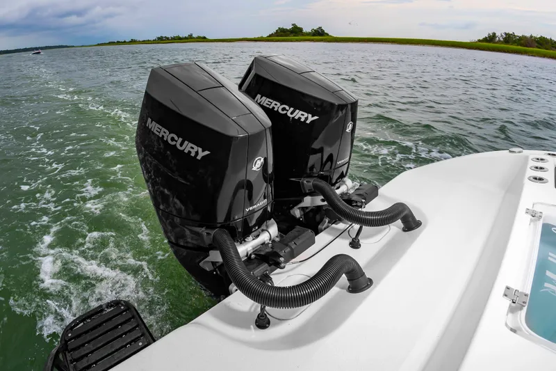 Slide: The Image of Two Mercury outboard engines on a boat in calm waters with a green shoreline in the background. - 14