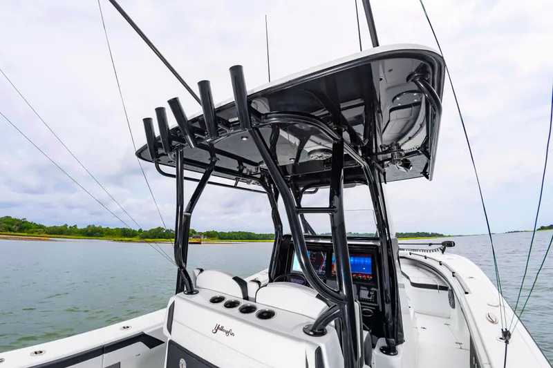 Slide: The Image of The image shows a modern boat with a black T-top and multiple fishing rod holders. - 26
