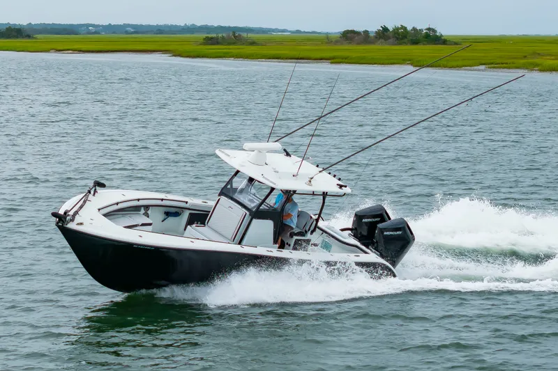 Slide: The Image of A black boat speeds across the water, featuring two outboard engines and fishing rods. - 46