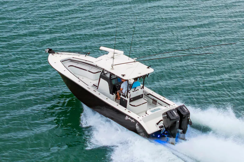 Slide: The Image of A 2025 Yellowfin 32 Offshore boat speeds across the water, featuring two outboard engines. - 3
