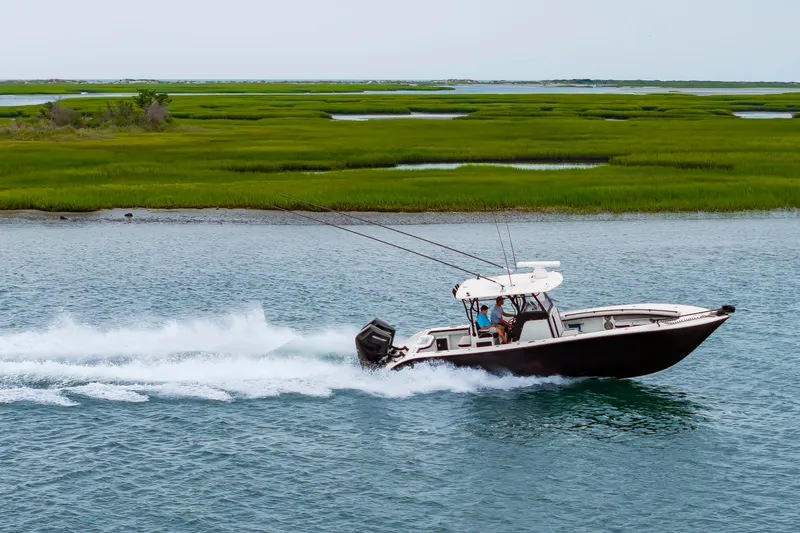 Slide: The Image of A 2025 Yellowfin 32 Offshore speeds through the water, surrounded by lush marshland. - 8