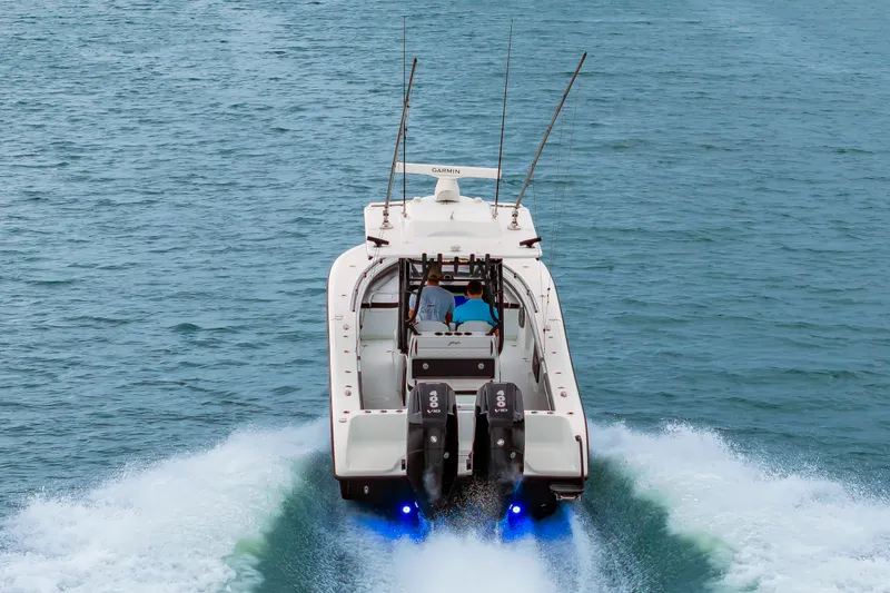 Slide: The Image of A 2025 Yellowfin 32 Offshore boat speeds across the water. It features twin outboard engines and fishing rod holders. - 6