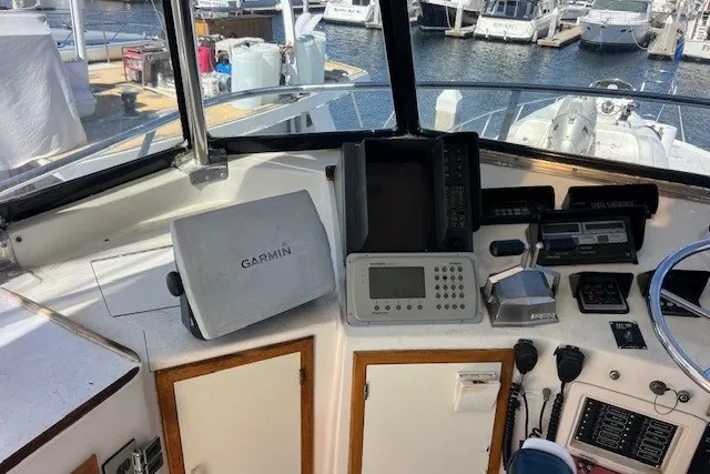 Slide: The Image of Cockpit of a 1994 Mikelson 64 yacht with navigation equipment and marina view. - 60