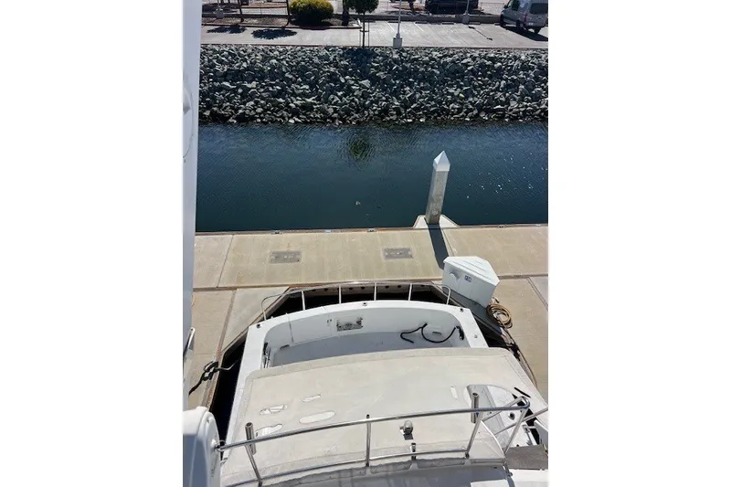 Slide: The Image of 1994 Mikelson 64 yacht docked at a marina with calm water and rocky shoreline. - 67