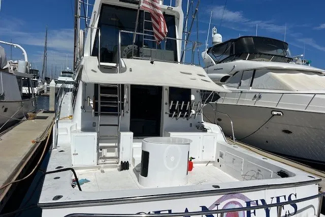 Slide: The Image of 1994 Mikelson 64 yacht docked at marina, featuring spacious deck and American flag. - 31