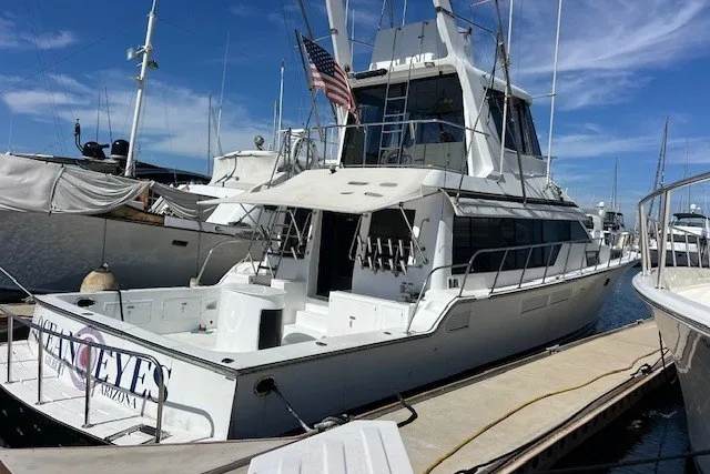 The Image of 1994 Mikelson 64 yacht docked at marina, featuring spacious deck and American flag. - 0