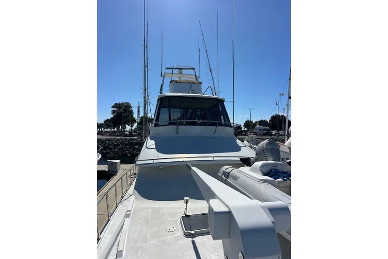 Slide: The Image of 1994 Mikelson 64 yacht docked, showcasing sleek design and spacious deck under clear blue sky. - 36