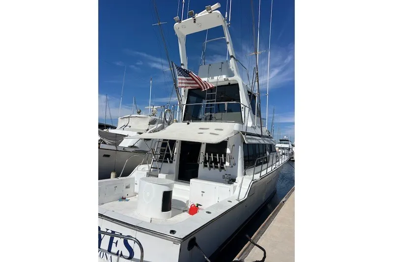 Slide: The Image of 1994 Mikelson 64 yacht docked, featuring a spacious deck and American flag. - 35