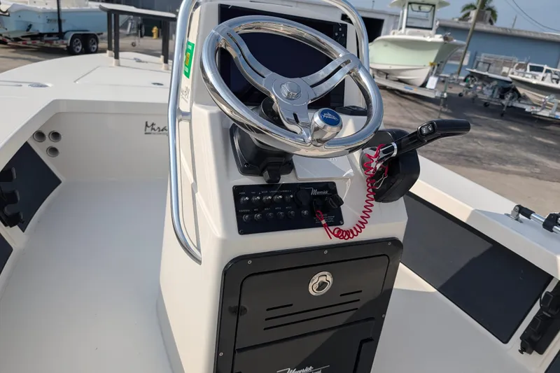 Slide: The Image of 2021 Maverick 18 HPX-V boat console with steering wheel and controls in a marina setting. - 14