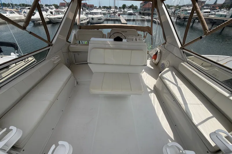 Slide: The Image of Interior view of a 1999 Carver 380 Santego yacht with white seating and marina backdrop. - 24