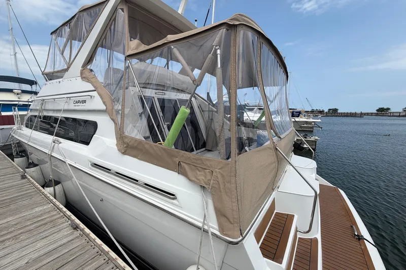 Slide: The Image of 1999 Carver 380 Santego yacht docked at marina, featuring tan canopy and clear windows. - 9