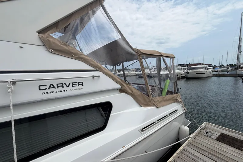 Slide: The Image of 1999 Carver 380 Santego yacht docked at marina, featuring sleek design and clear canopy. - 8