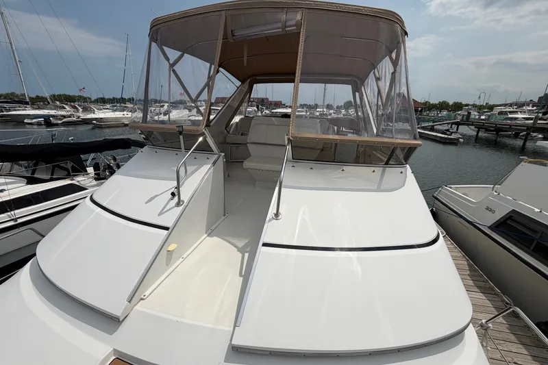 Slide: The Image of 1999 Carver 380 Santego yacht docked at marina, featuring spacious deck and clear canopy. - 30