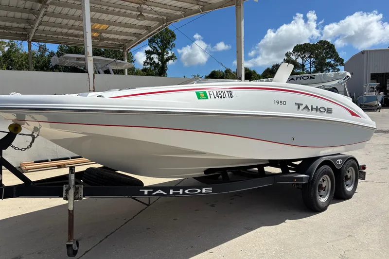The Image of White 2022 Tahoe 1950 boat on trailer under canopy, sunny day. - 0