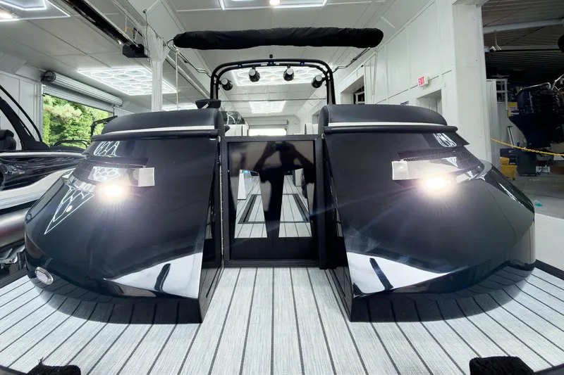 Slide: The Image of 2025 Montara Surf Boss 2.0 - SL 25' boat in showroom, sleek black design, illuminated lights. - 2
