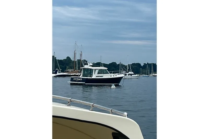 Slide: The Image of 2018 Back Cove 37 boat anchored in a serene marina with sailboats in the background. - 1