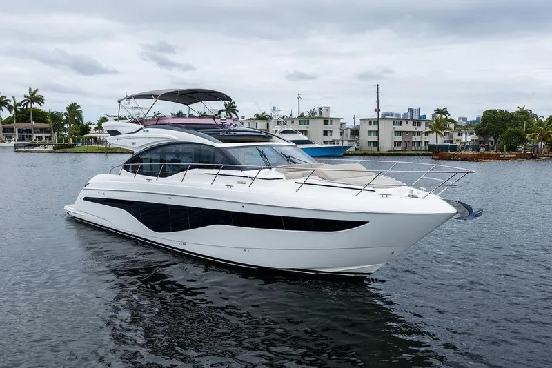 Slide: The Image of 2020 Princess S62 yacht on calm water, modern design, luxury waterfront homes in background. - 4