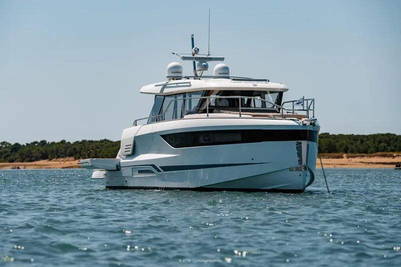 Slide: The Image of 2026 Wellcraft 44 Explorer yacht anchored on calm water with scenic shoreline backdrop. - 22