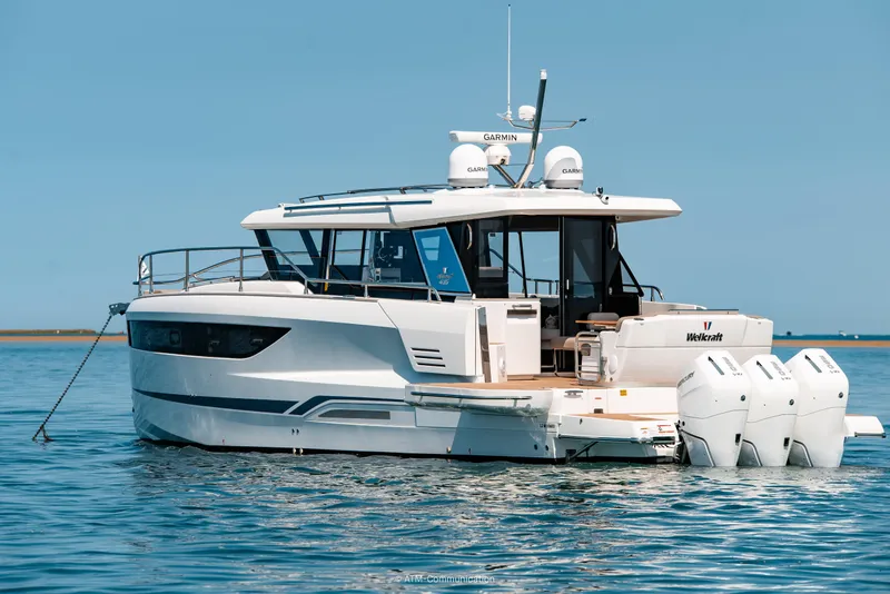 Slide: The Image of 2026 Wellcraft 44 Explorer yacht on calm blue water, featuring triple outboard engines. - 23