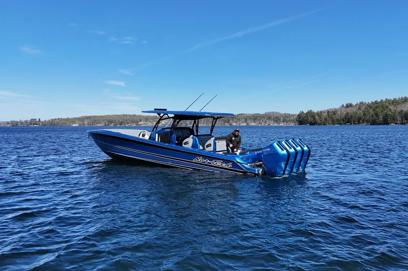 The Image of 2026 Nor-Tech 390 Sport boat on a serene lake under a clear blue sky. - 1