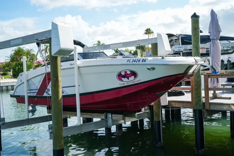 Slide: The Image of 2018 Four Winns HD240 OB boat, labeled "The Batboat," docked on a lift by the water. - 50