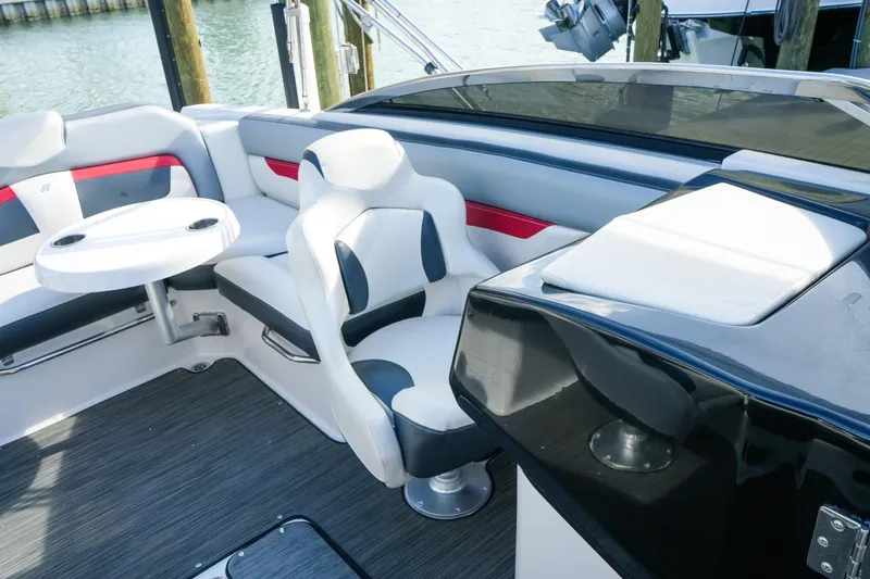 Slide: The Image of 2018 Four Winns HD240 OB boat interior with seating and table, docked by the water. - 34