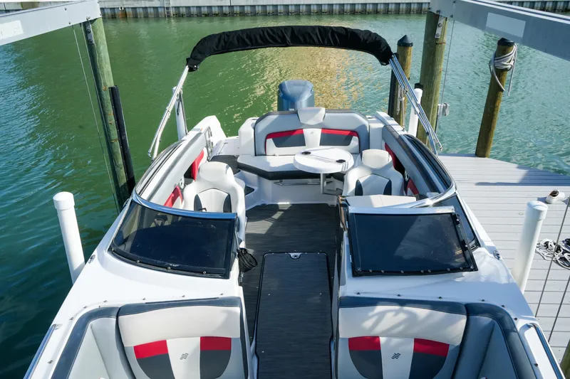 Slide: The Image of 2018 Four Winns HD240 OB boat interior with seating and table, docked on calm water. - 29