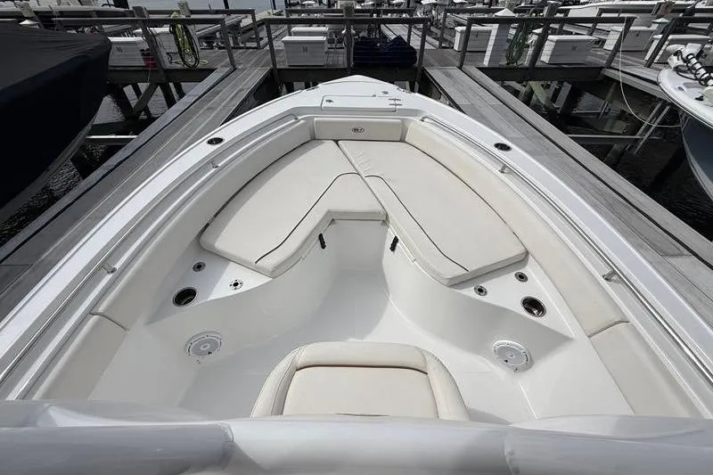 Slide: The Image of 2022 Sea Hunt Ultra 234 boat interior with white cushioned seating at dock. - 22