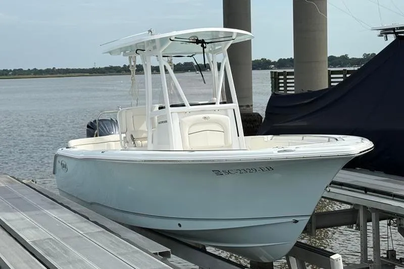 Slide: The Image of 2022 Sea Hunt Ultra 234 boat docked by the water. - 2